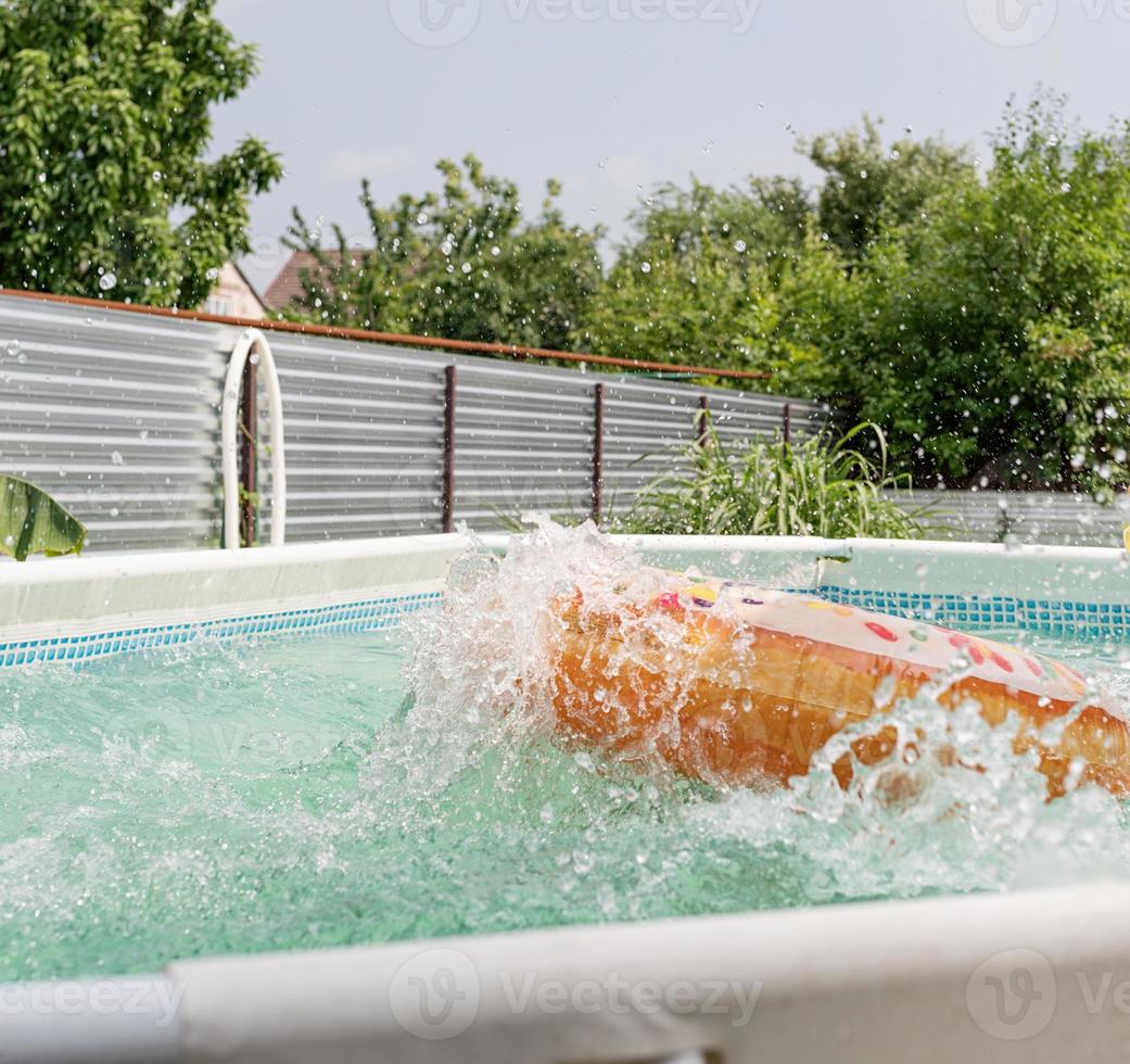 Tubo de natación en forma de rosquilla en la piscina con salpicaduras foto