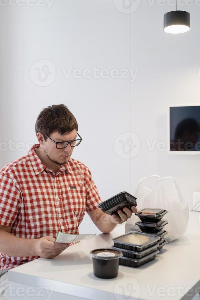 Young man sorting food delivery boxes at the modern kitchen photo