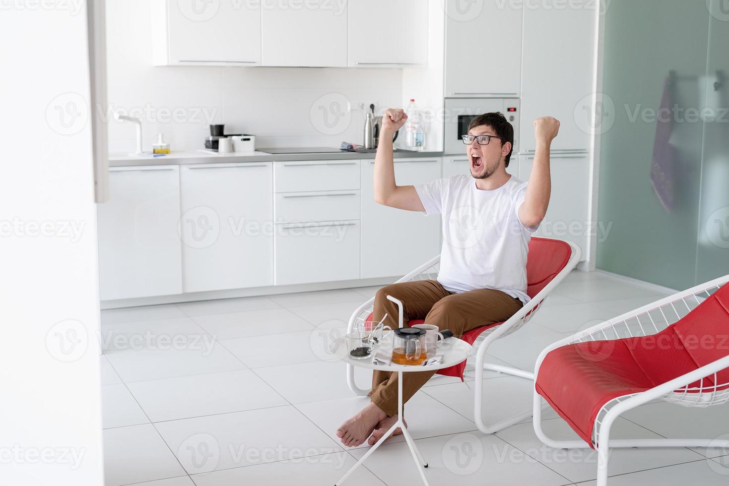 Joven viendo un juego de deportes, animando y gritando. foto