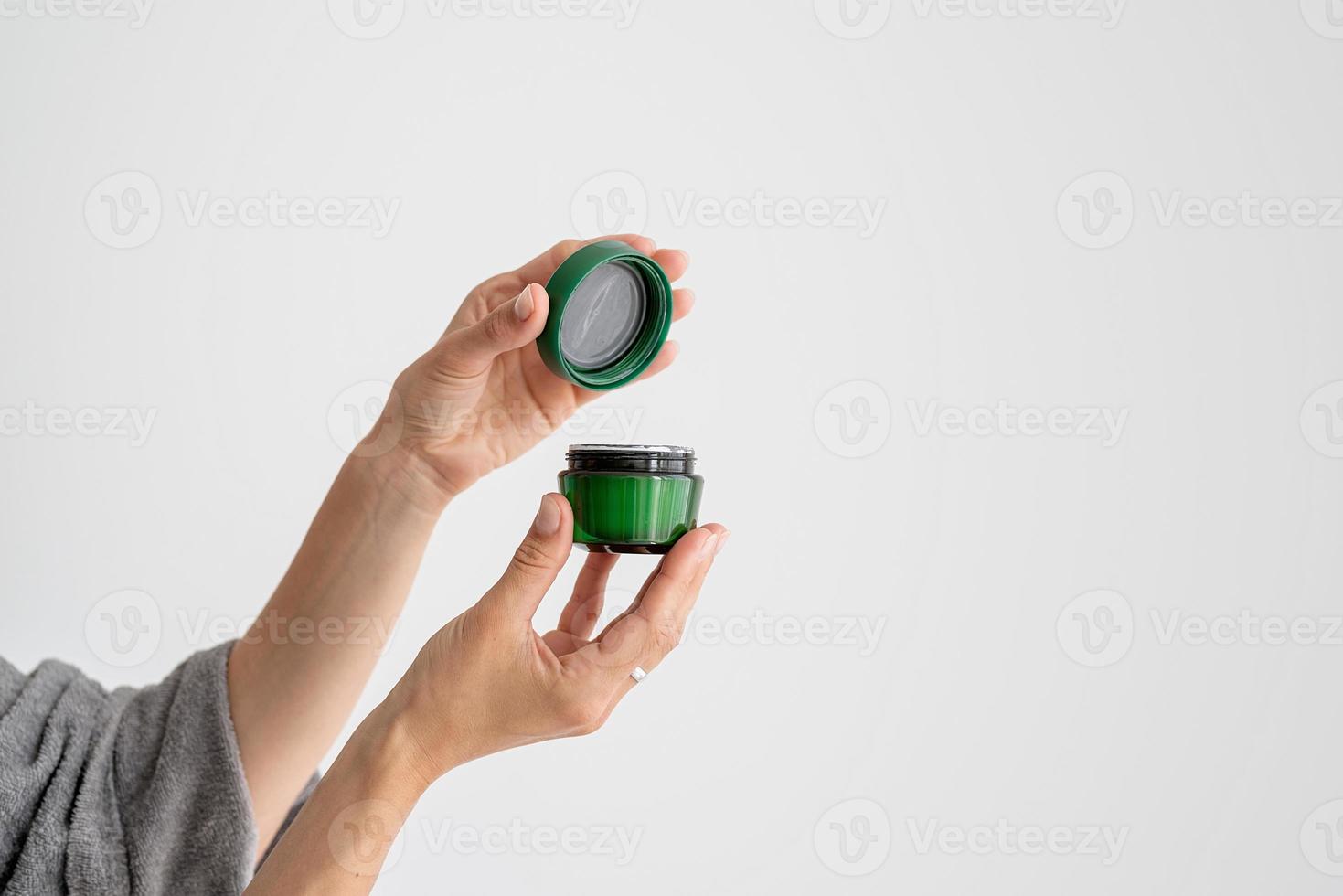 Young woman holding jar with face mask photo