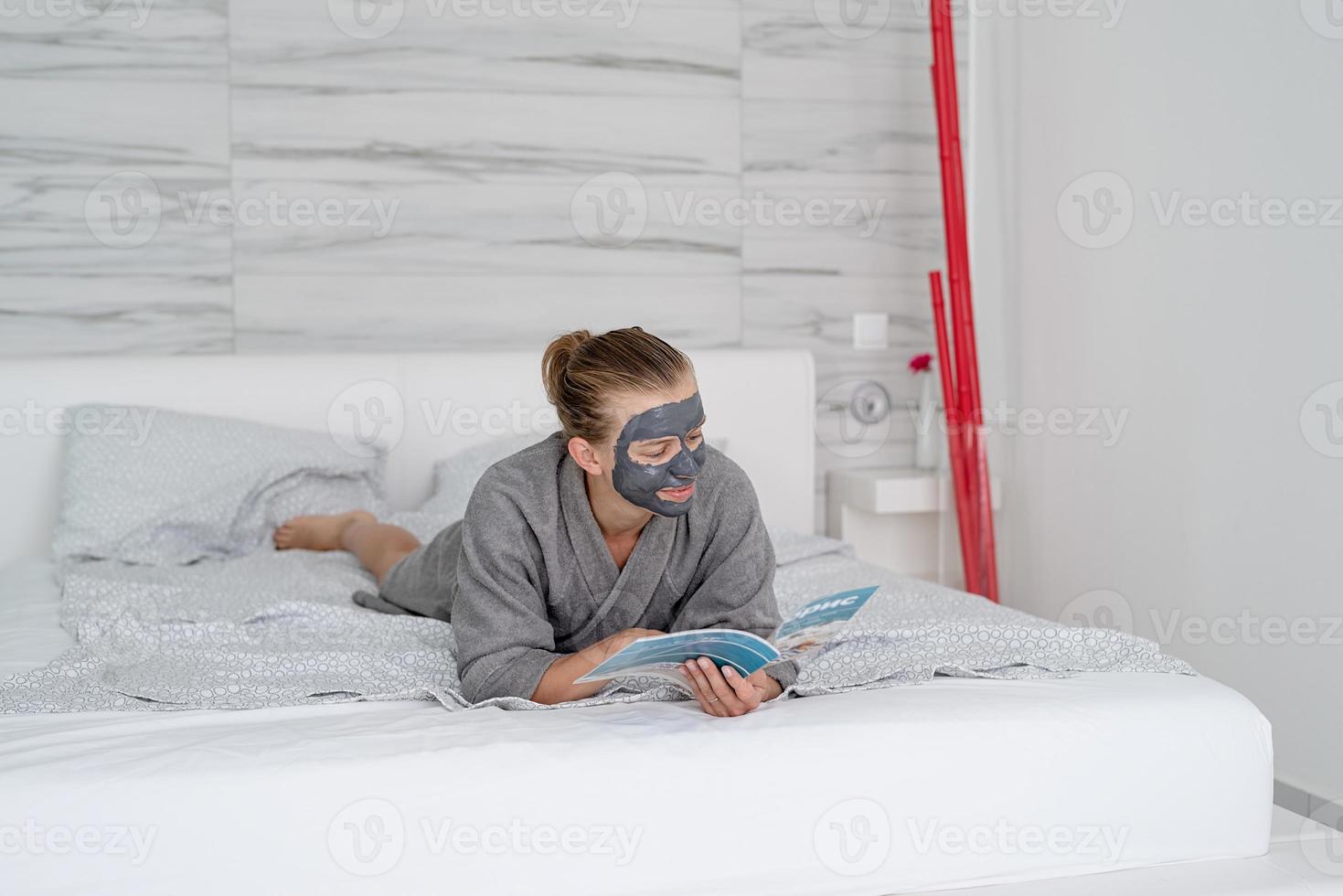 Mujer con mascarilla relajante acostado en la cama leyendo una revista foto