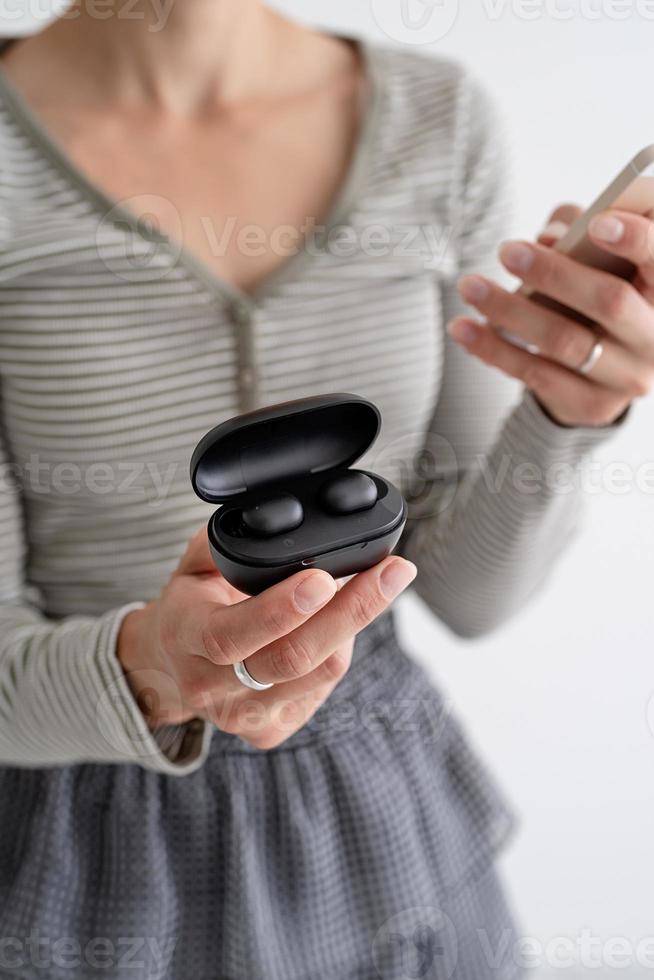Young woman holding wireless earbuds photo