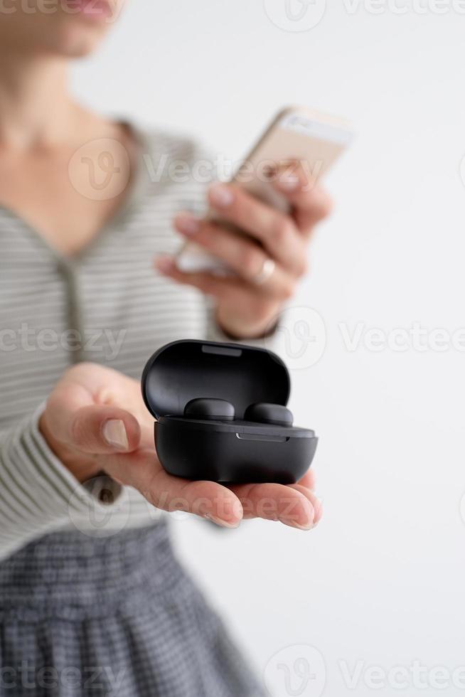 Young woman holding wireless earbuds photo
