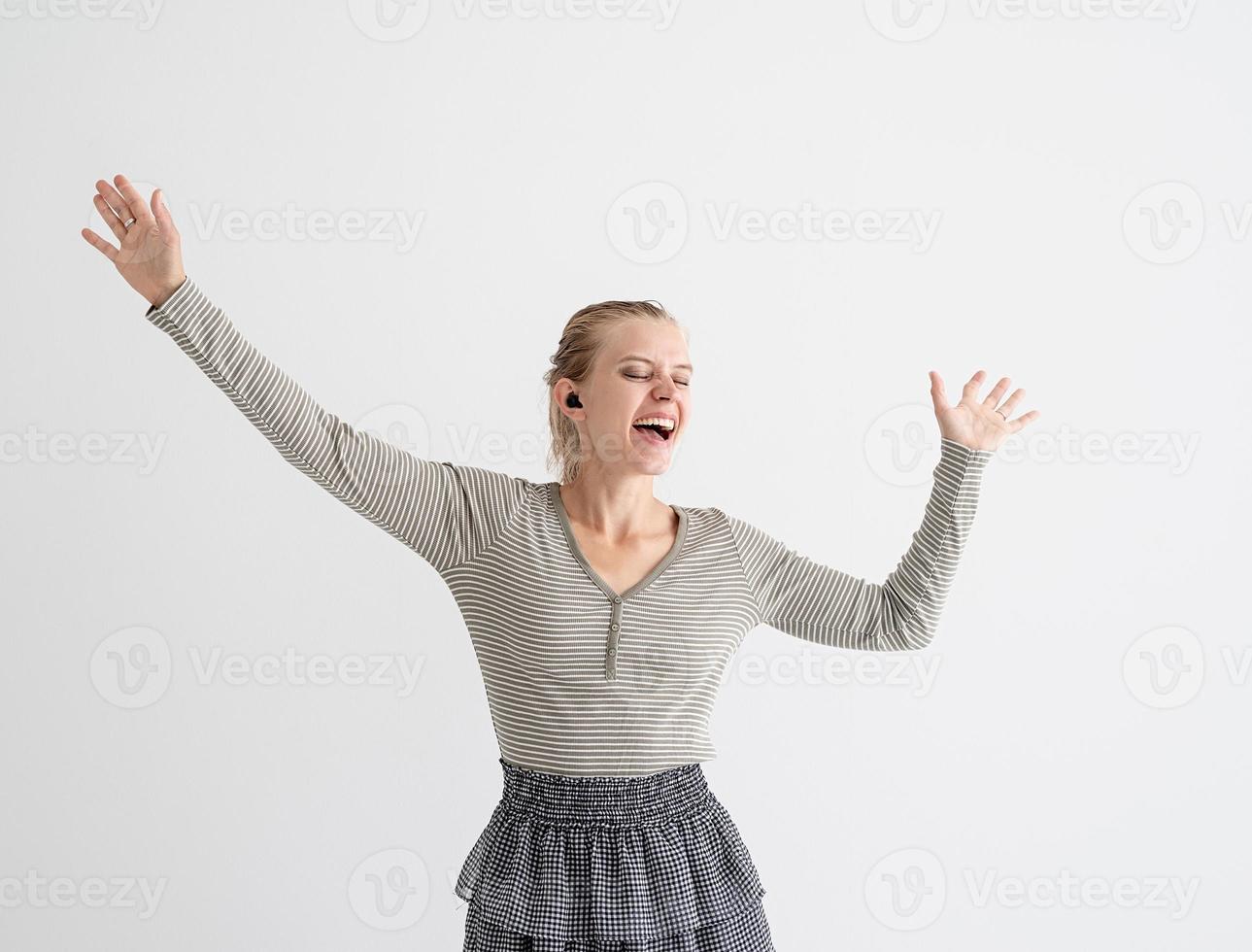 Young woman holding wireless earbuds and dancing photo