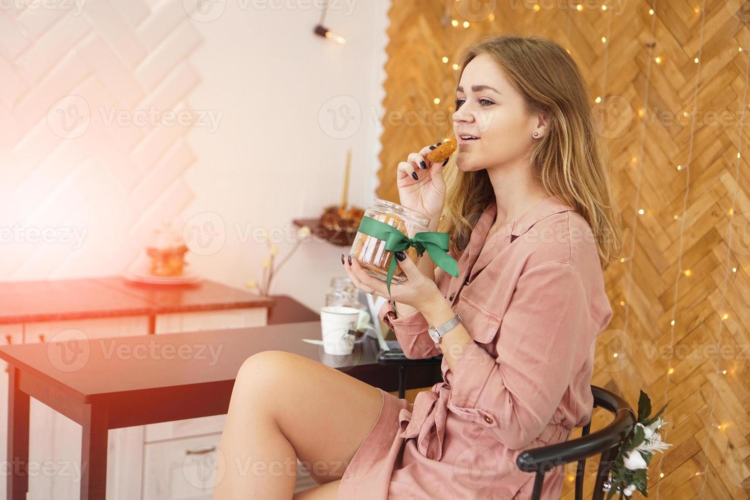 Happy young woman having eating christmas cookies in kitchen photo