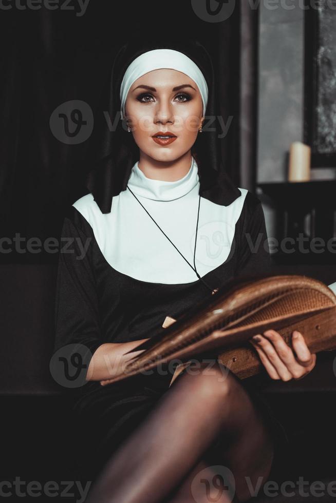 Beautiful young nun in religion black suit holds Bible. Religion photo