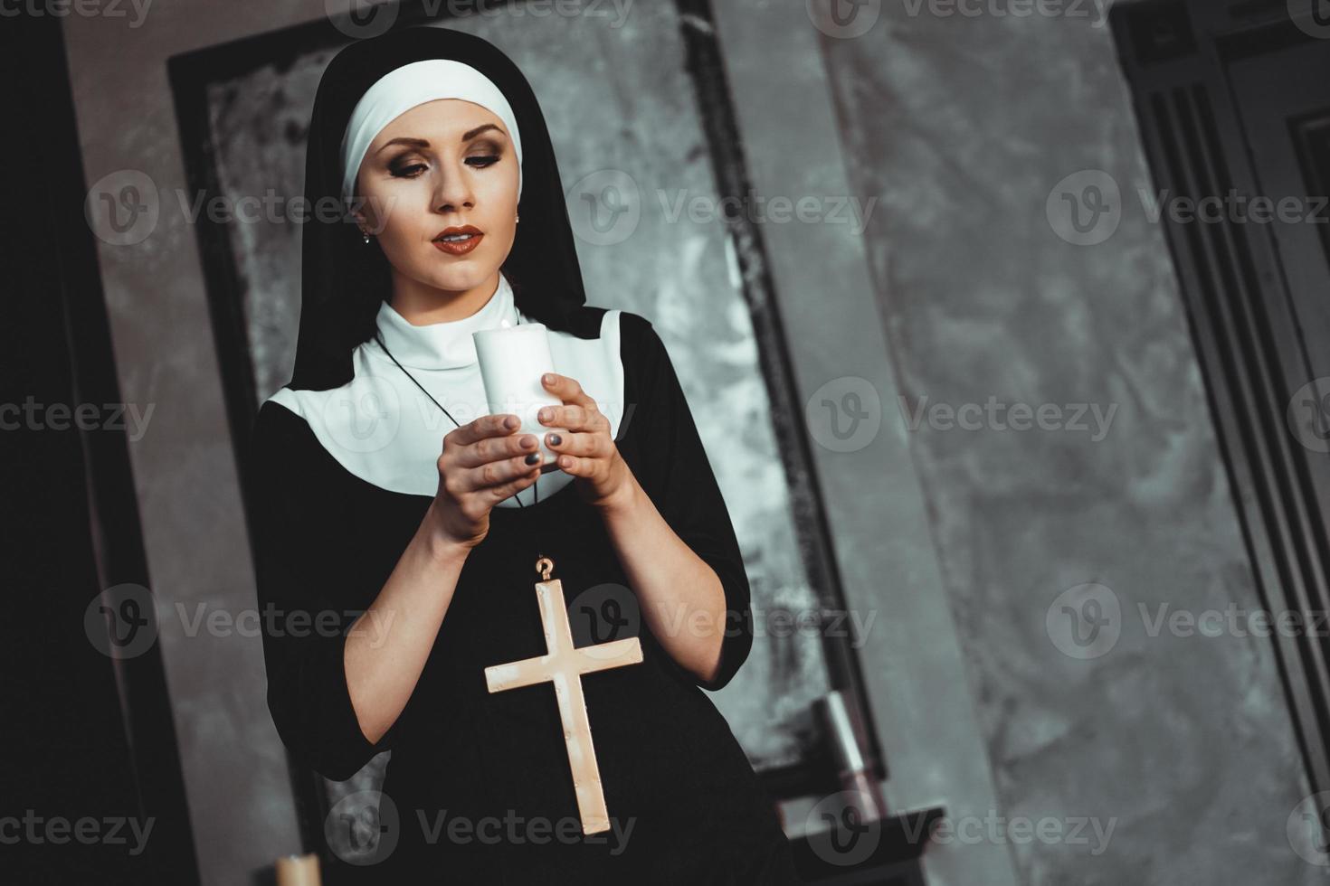 Young catholic nun is holding candle in her hands photo