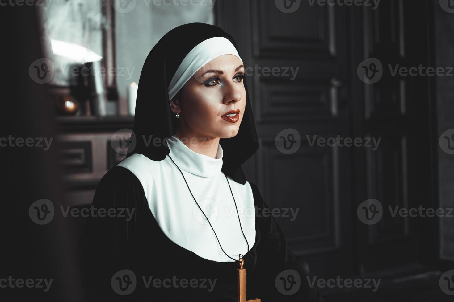 Sexy nun prays indoor. Beautiful young holy sister. photo