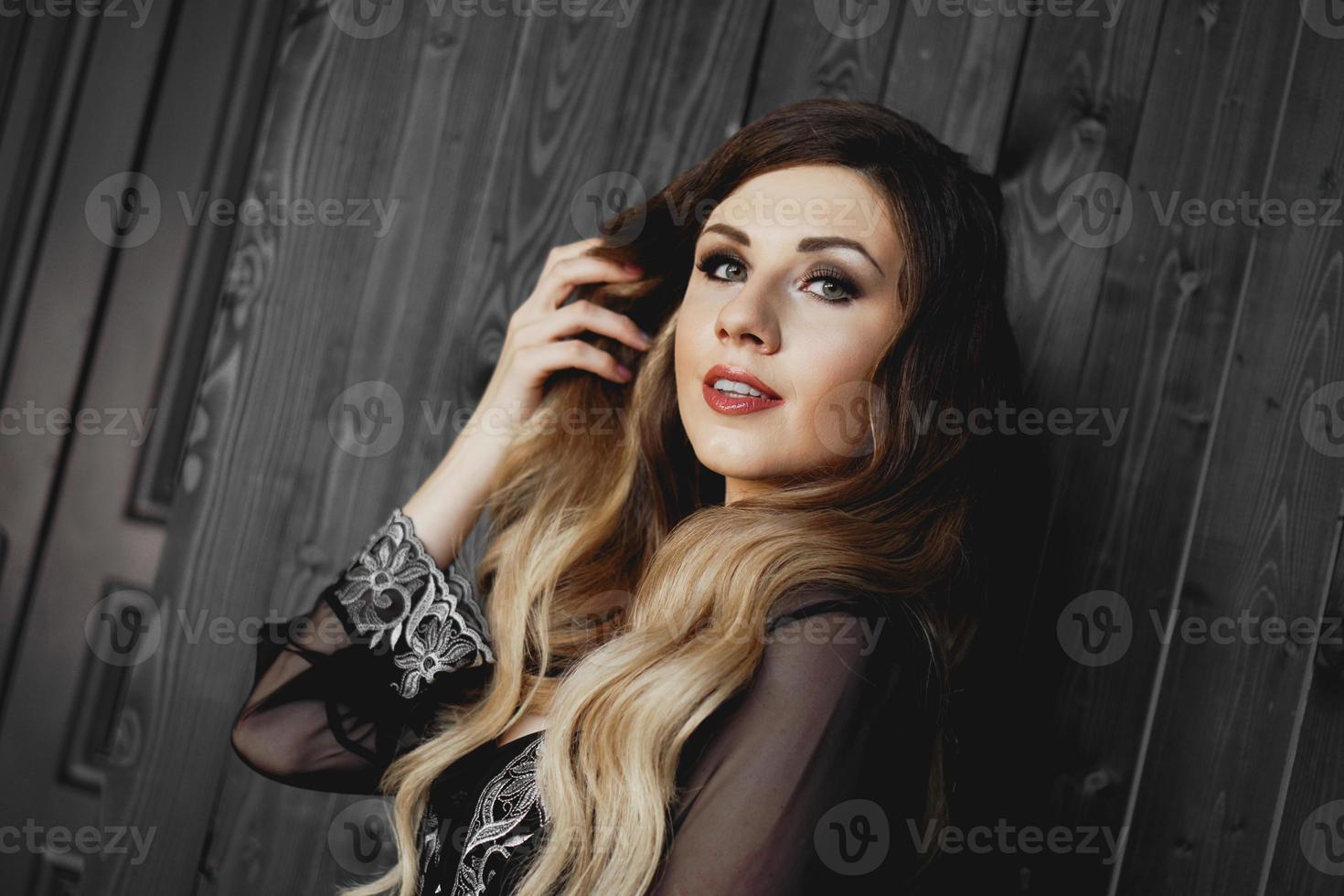 Mujer bonita joven, vestida con una bata negra transparente en una habitación oscura foto