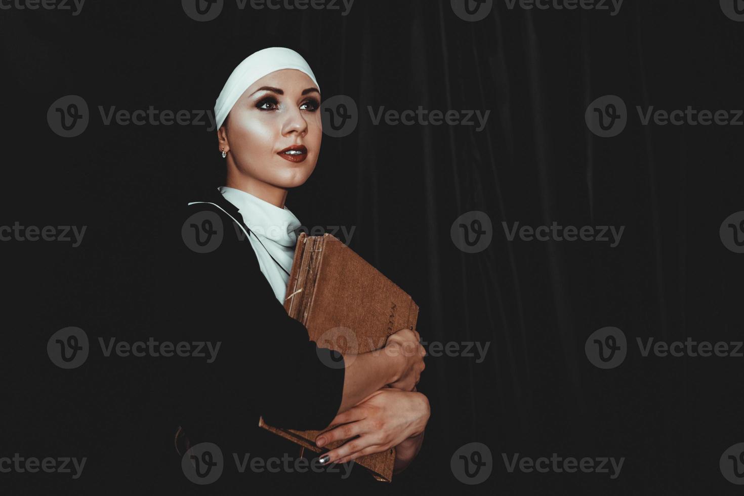 Beautiful young nun in religion black suit holds Bible. Religion photo