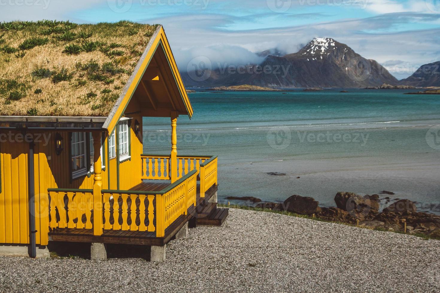 Casa de madera amarilla con musgo en el fondo del mar y las montañas foto