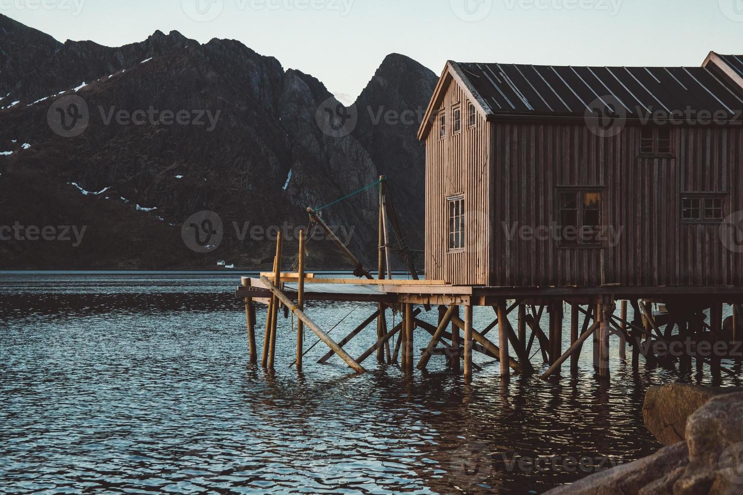 Antiguas casas de pesca de madera cerca del lago con el telón de fondo de las montañas foto