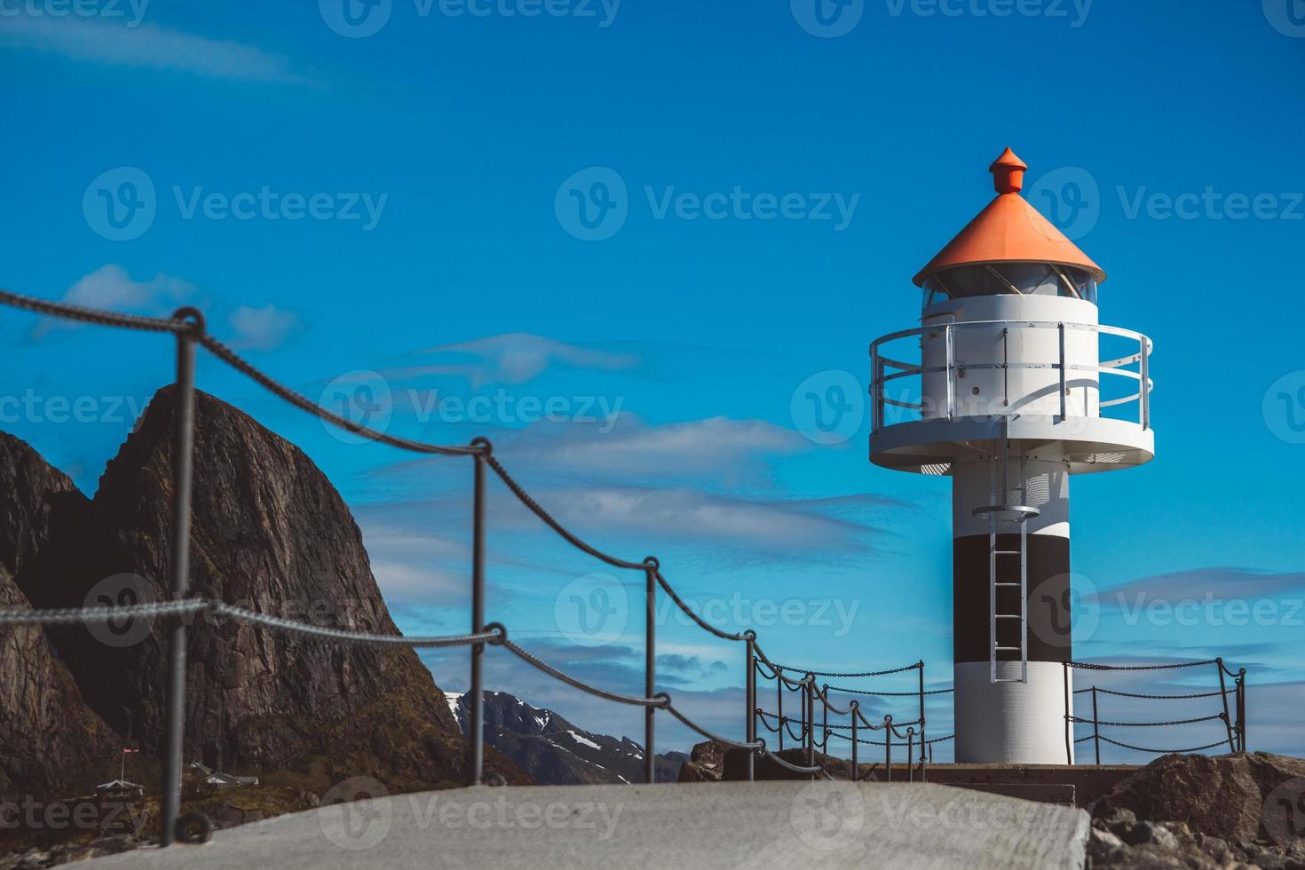 Lighthouse on pier on background of mountains and blue sky photo