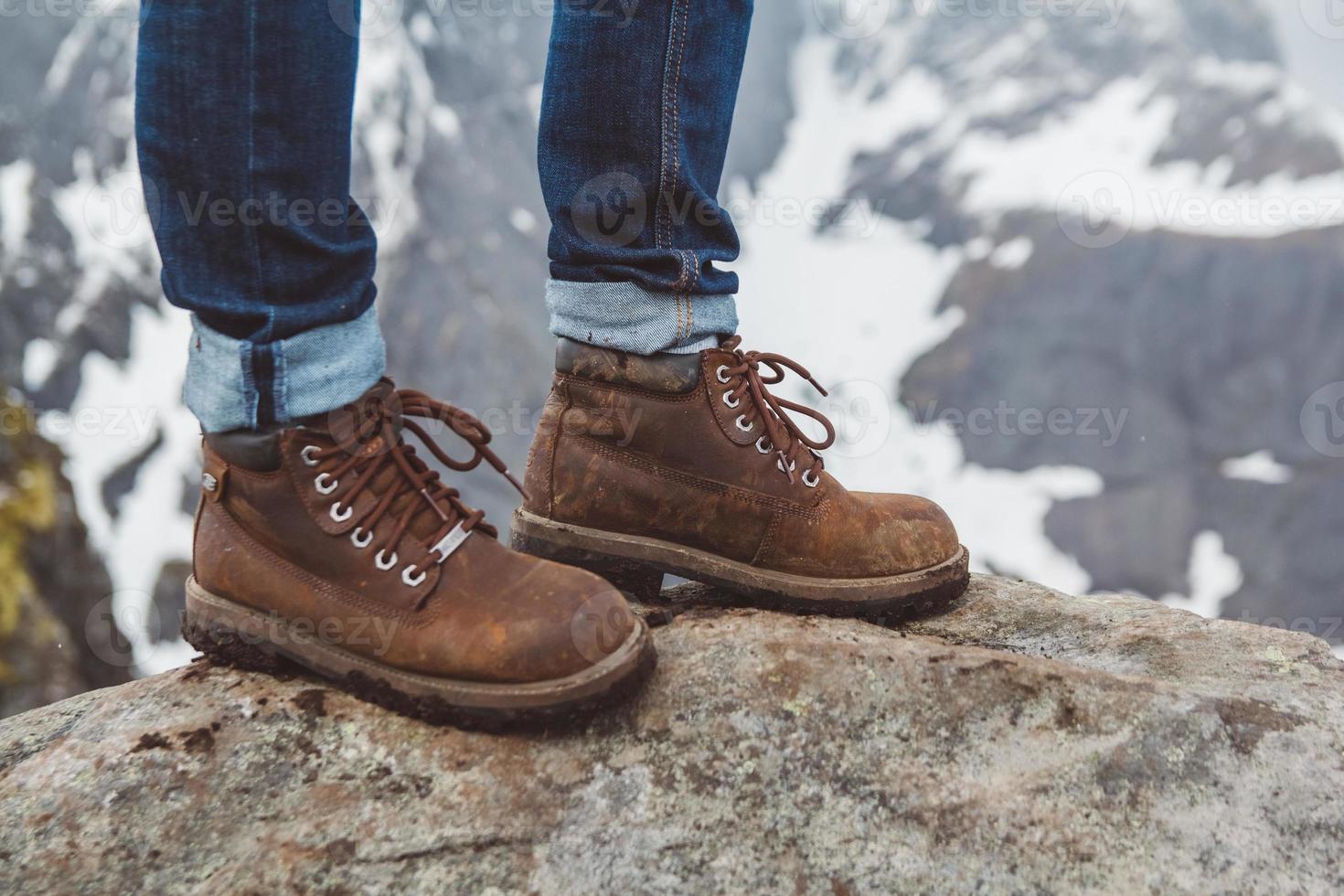 Piernas de un hombre con zapatos marrones sobre un fondo de montañas foto