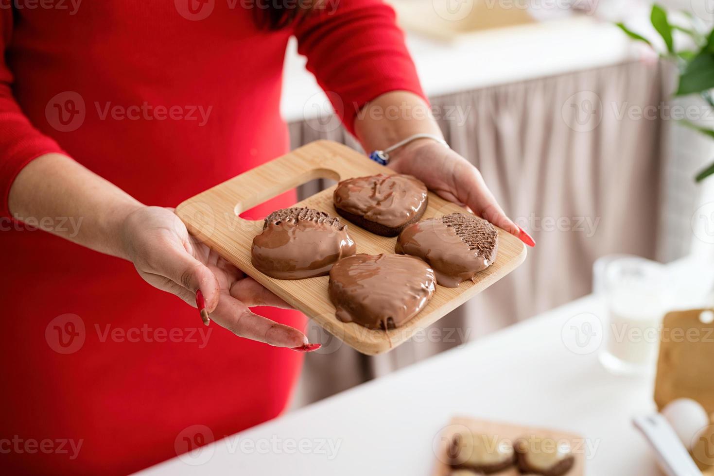 Woman in red dress making valentine cookies at the kitchen photo