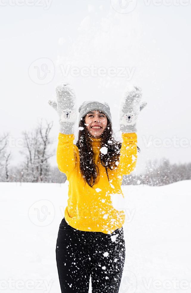 Young brunette woman playing with snow in park photo