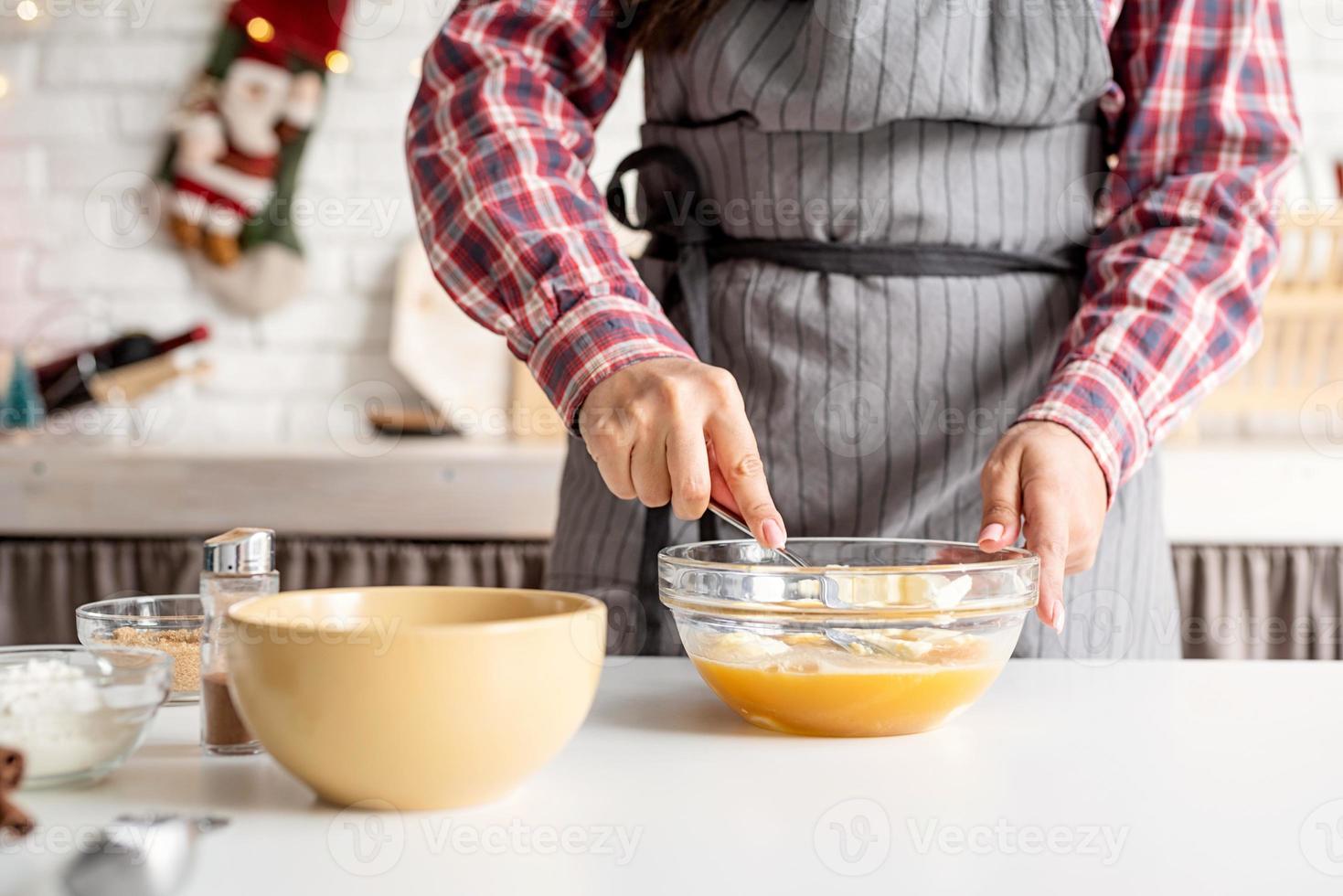 Joven latina batiendo huevos cocinar en la cocina foto