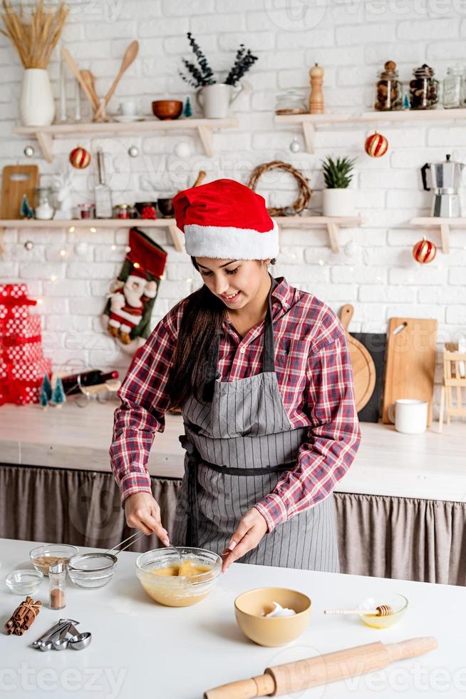 Joven mujer latina mezclar masa cocinar en la cocina foto