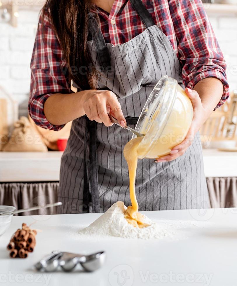 Joven mujer latina mezclar masa cocinar en la cocina foto