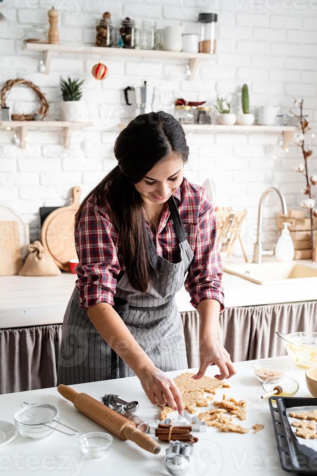 Joven mujer morena horneando galletas en la cocina foto