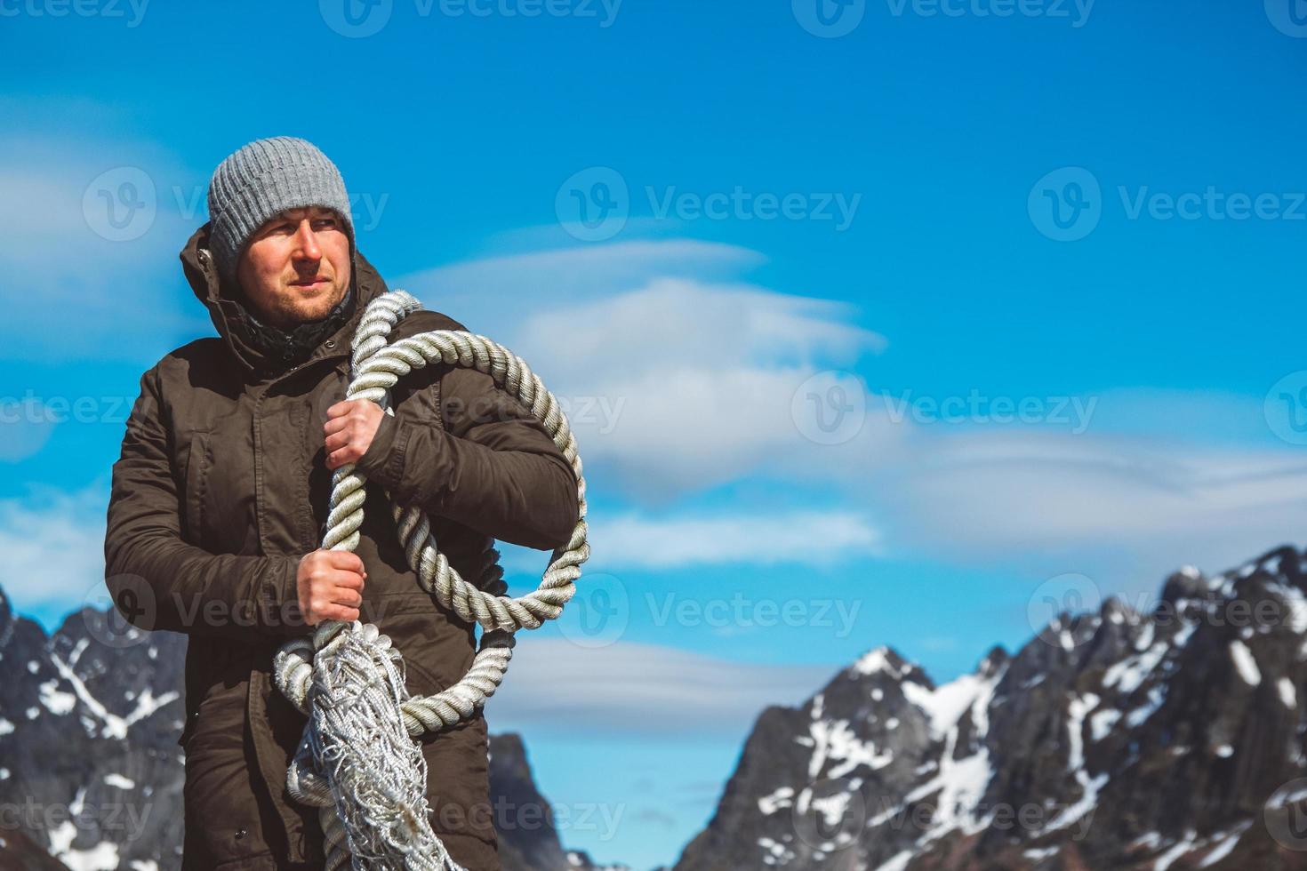 Hombre con una cuerda en el hombro contra un fondo de montañas foto