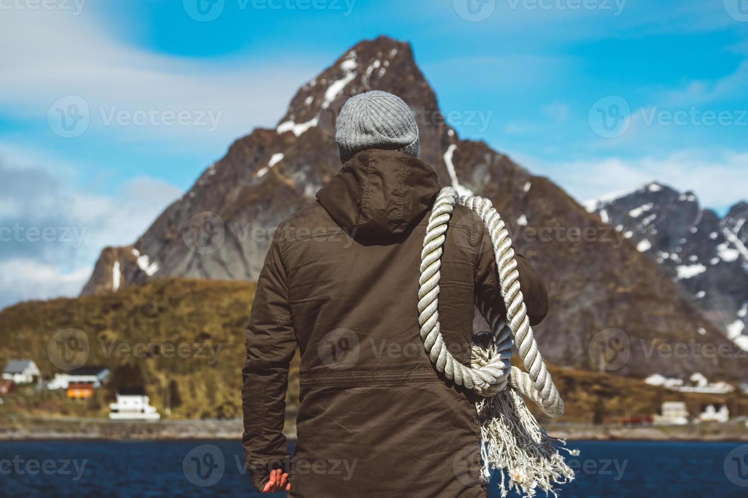 Man with a rope on his shoulder against a background of mountains photo