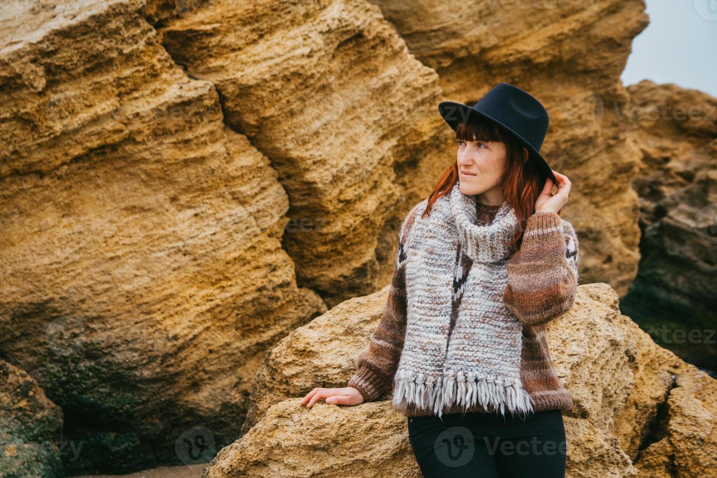 Mujer con sombrero y bufanda sobre fondo de rocas foto