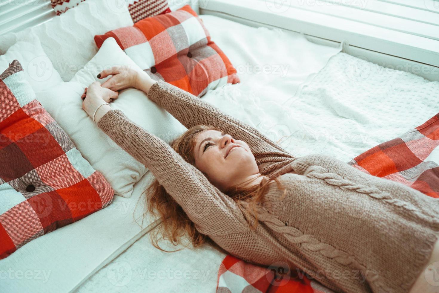 Happy woman lying on a bed and smiling photo