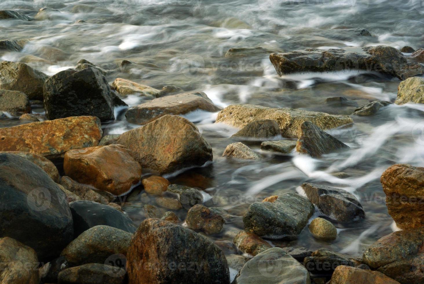 turbulencia de agua de mar y rocas en la costa foto