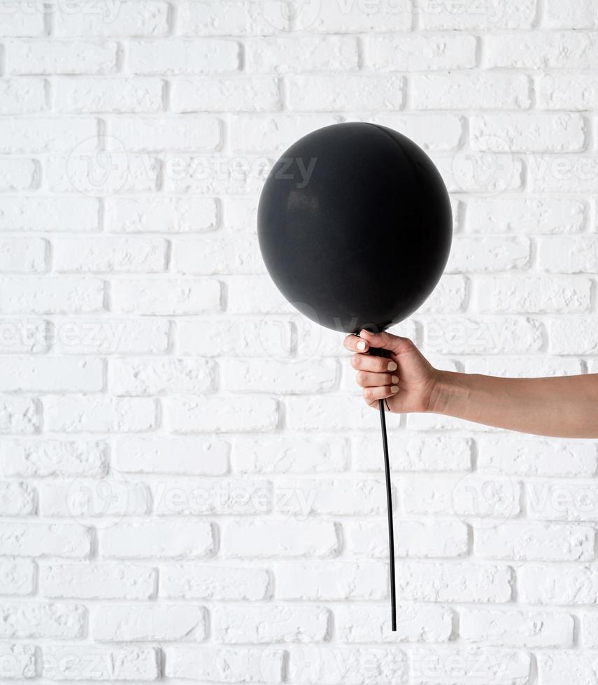 Woman hand holding black balloon on white background photo