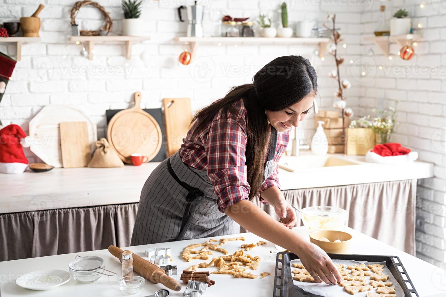 Joven mujer morena horneando galletas en la cocina foto