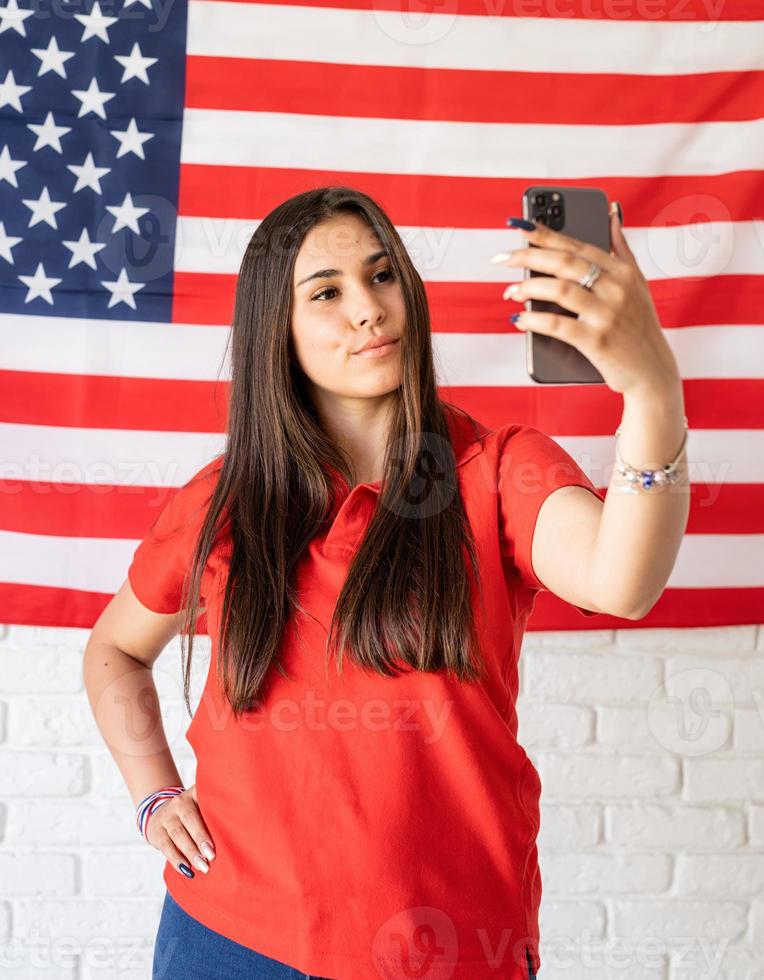 Beautiful woman taking a selfie on the USA flag background photo
