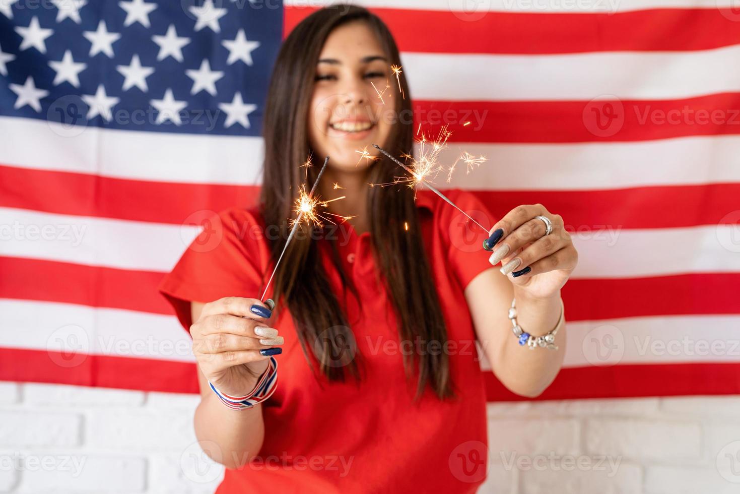 Bella mujer sosteniendo una bengala en el fondo de la bandera estadounidense foto