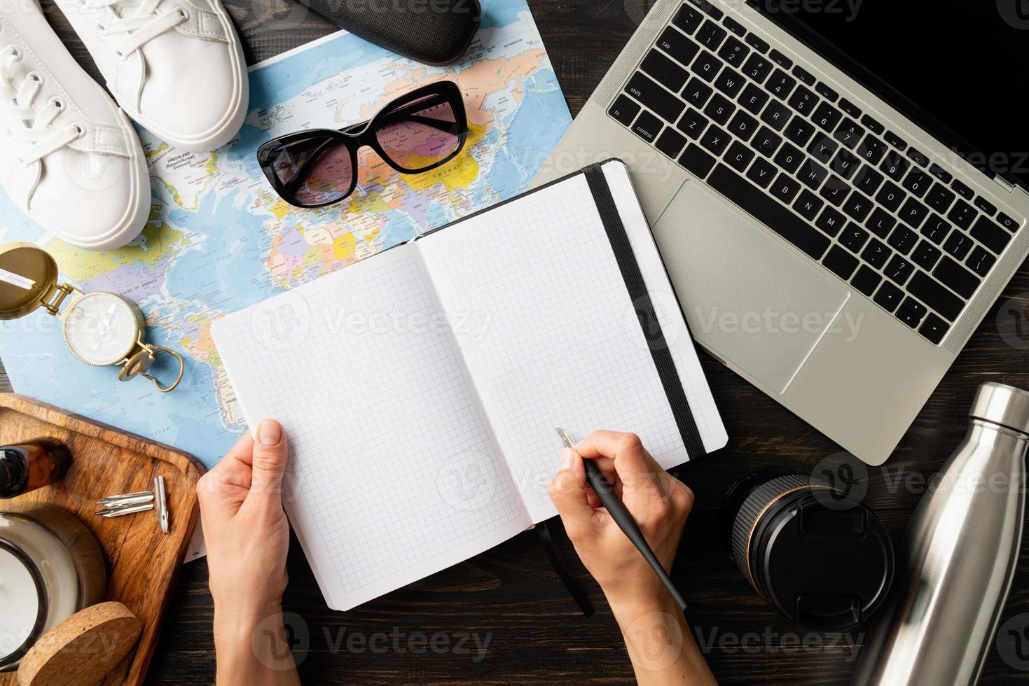 vista superior mujer planeando un viaje, escribiendo en un cuaderno foto