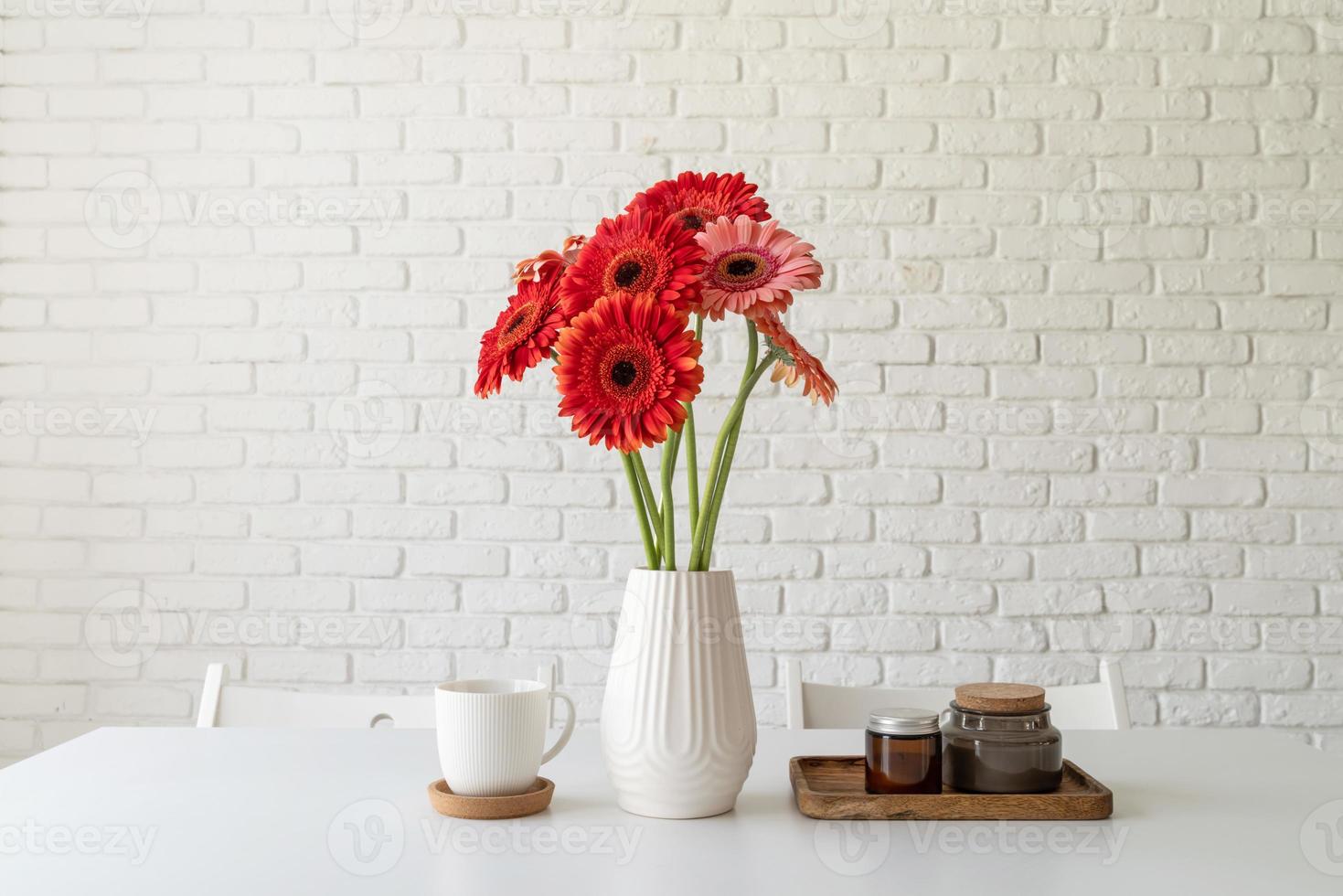 Bright gerbera daisies in white vase on kitchen table, minimal style photo