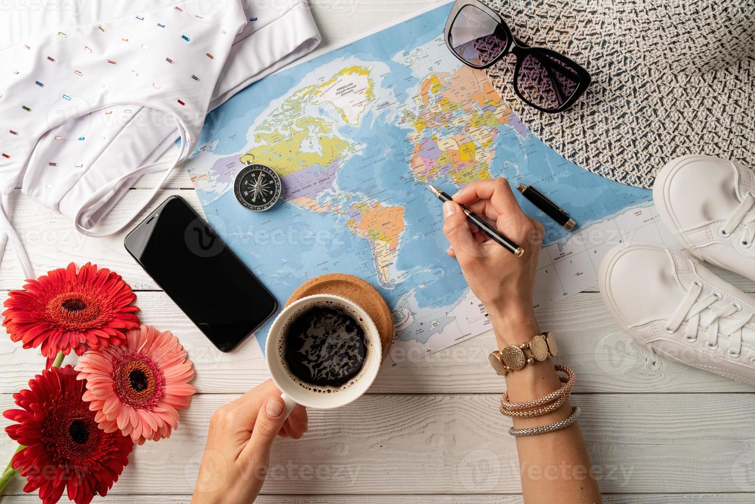 mujer de vista superior planeando un viaje, tomando café y dibujando en un mapa foto