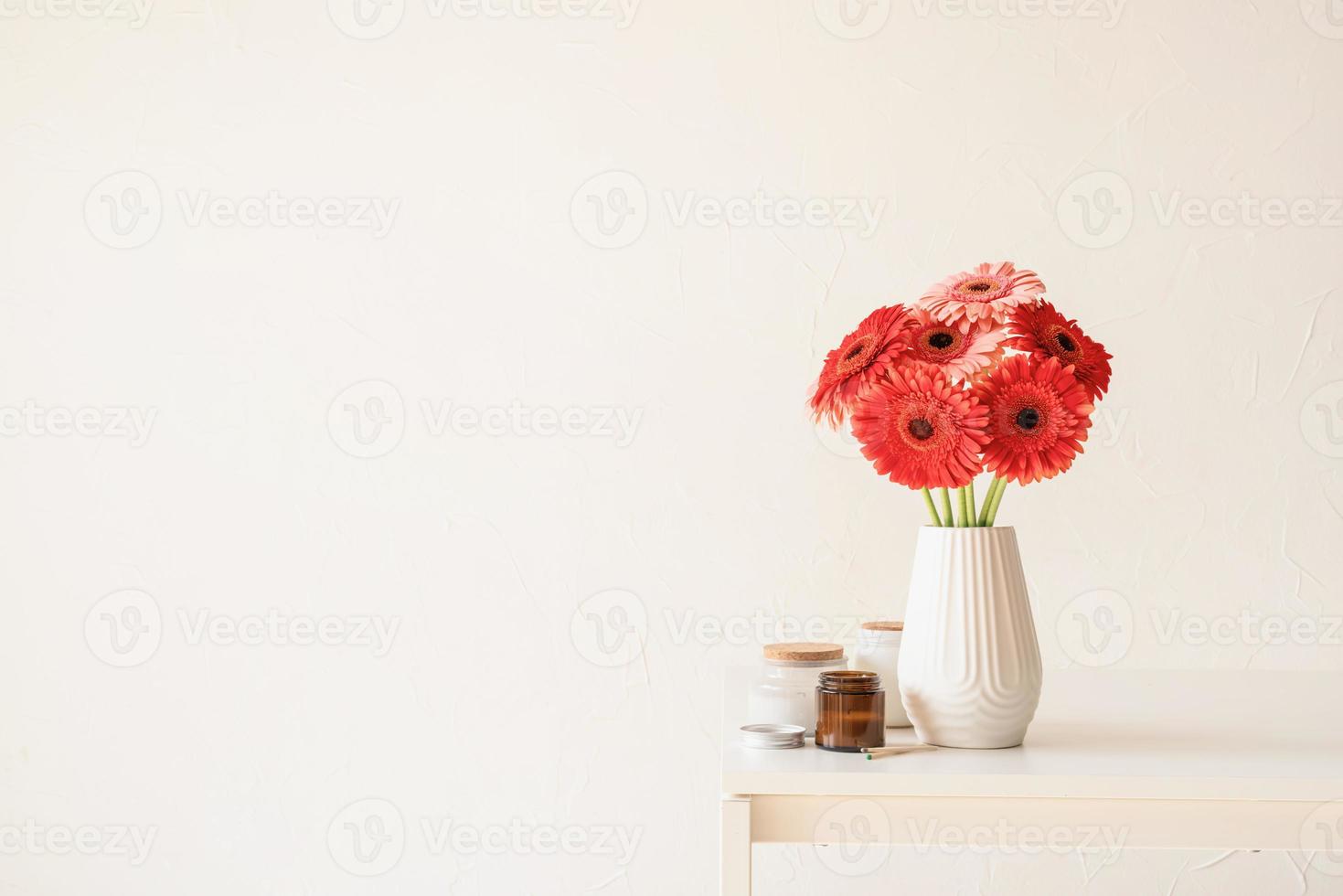 Margaritas gerberas brillantes en jarrón blanco sobre la mesa de la cocina, estilo minimalista foto