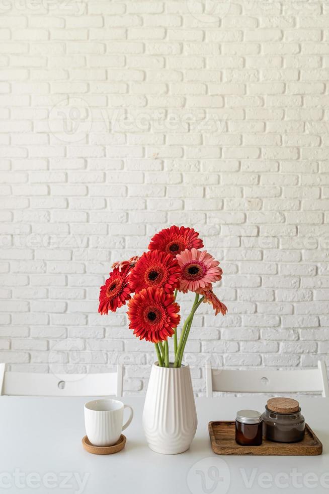 Bright gerbera daisies in white vase on kitchen table, minimal style photo