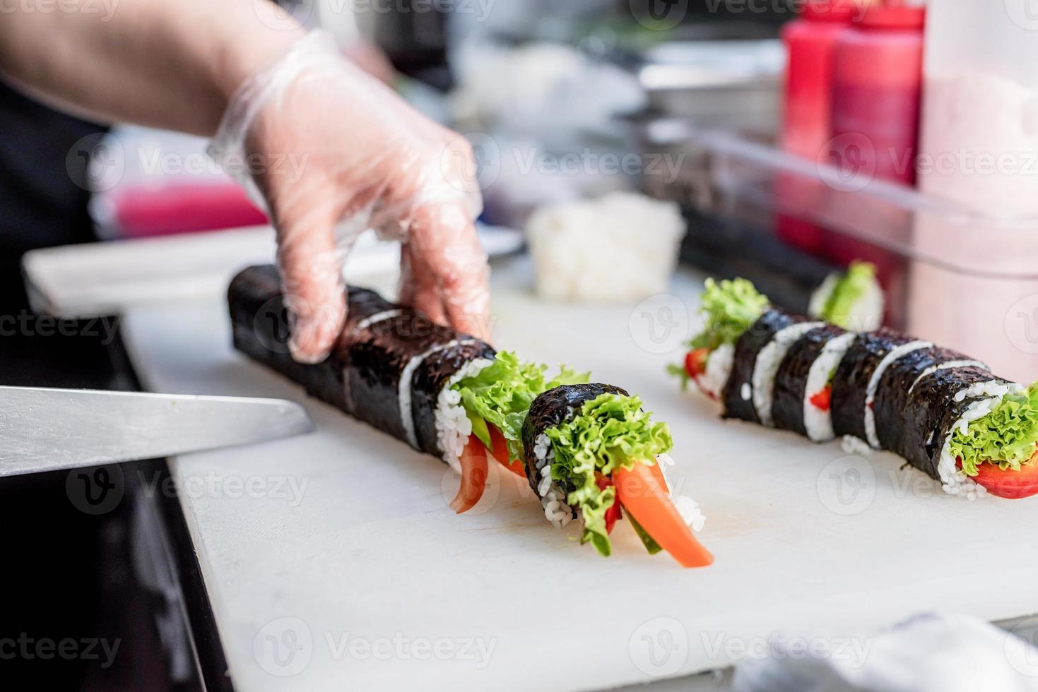 Sushi chef slicing rolls photo