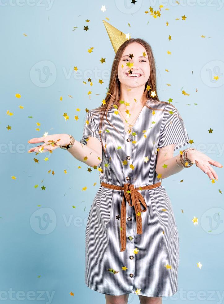 Tennager girl blowing confetti over blue background photo