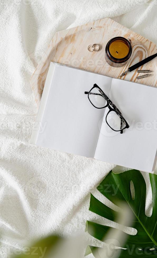 Opened book, glasses, candle and flowers . Mock up design photo