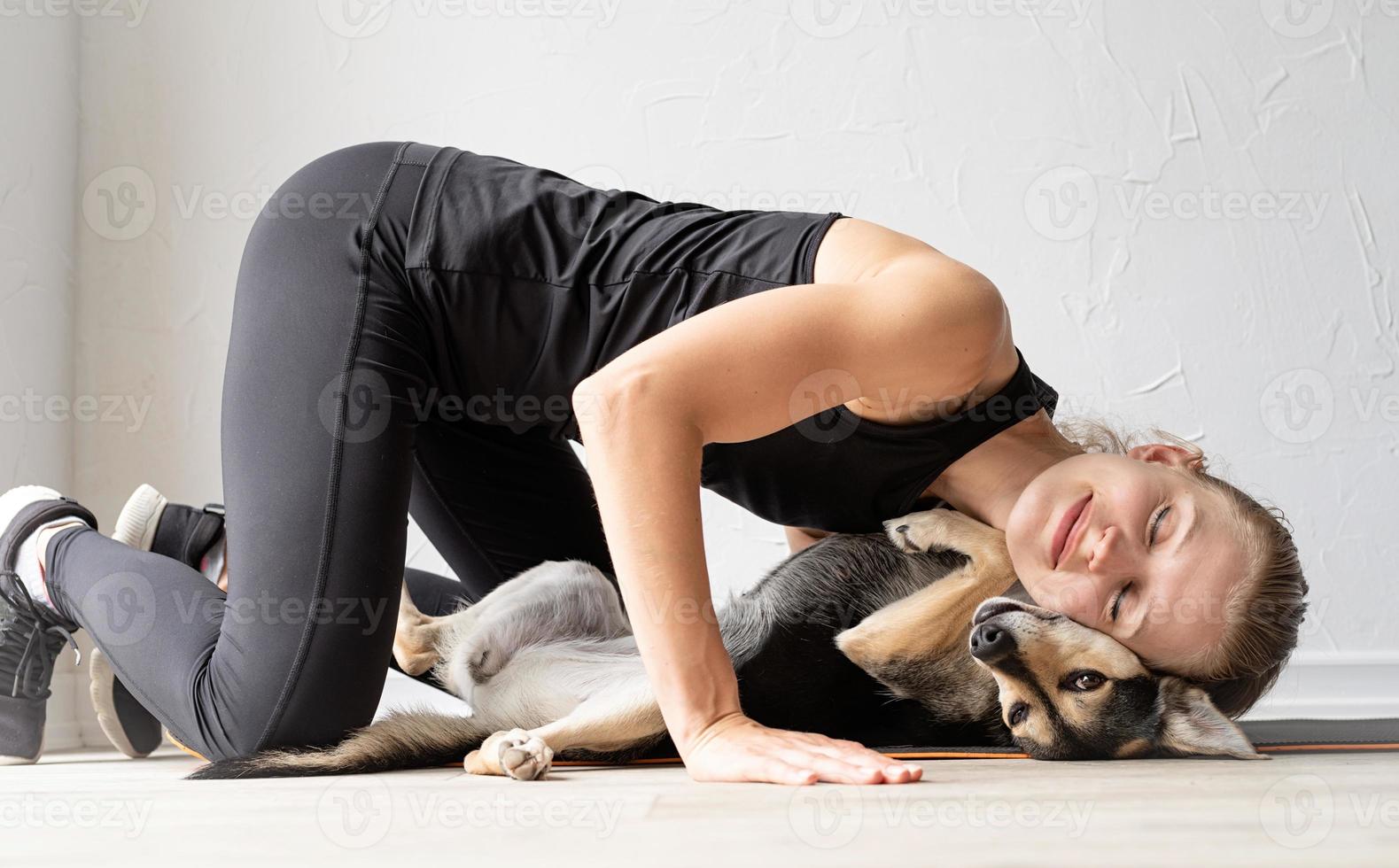 Joven deportiva abrazando a su perro de raza mixta foto