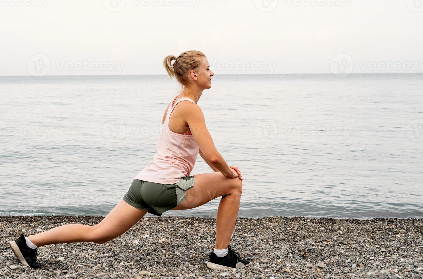 Blong athlete woman doing exercises at the beach photo