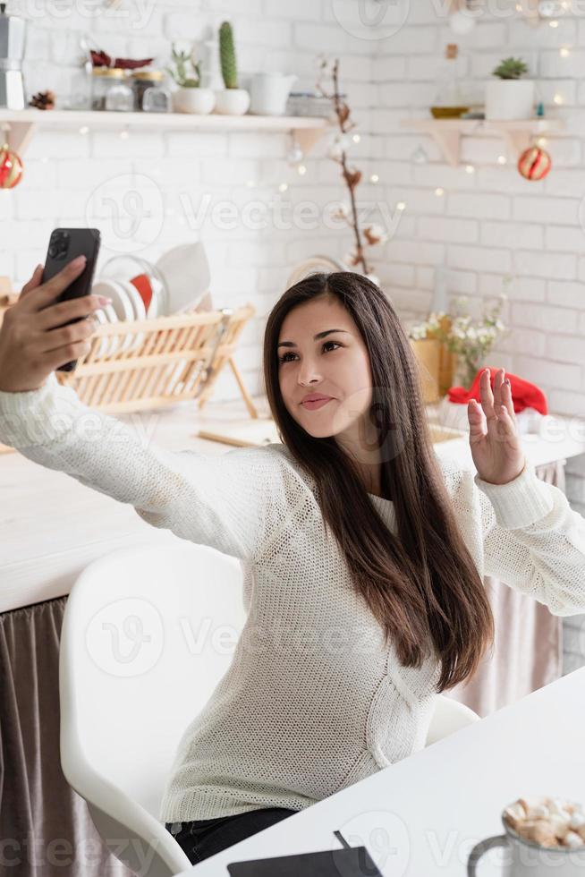 Woman chatting with friends using her mobile phone at the kitchen photo