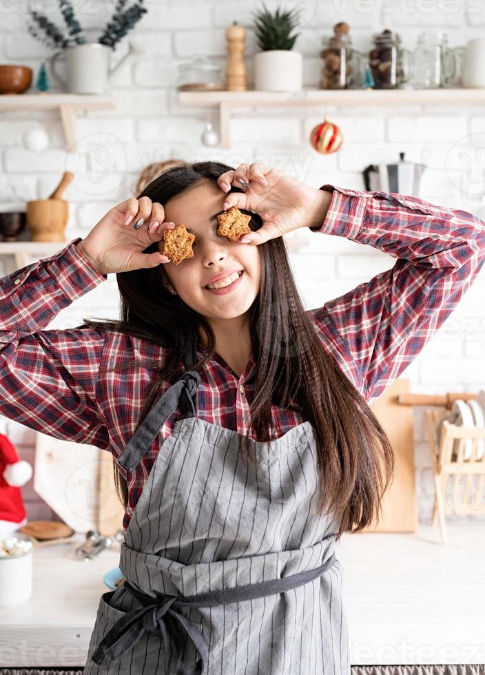 Mujer en delantal sosteniendo galletas en forma de estrella delante de sus ojos foto