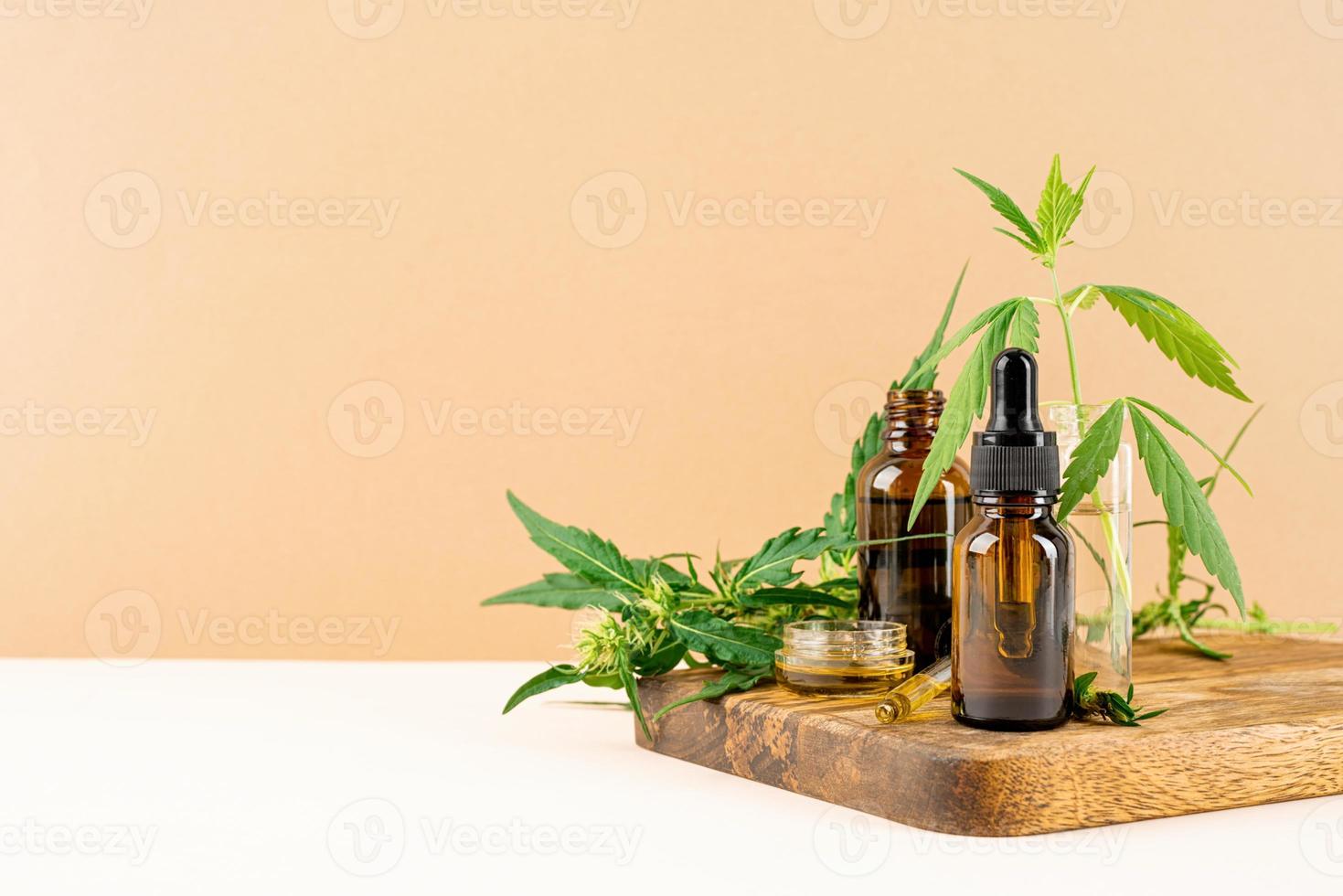 Cbd oil and cannabis leaves cosmetics front view on orange background photo