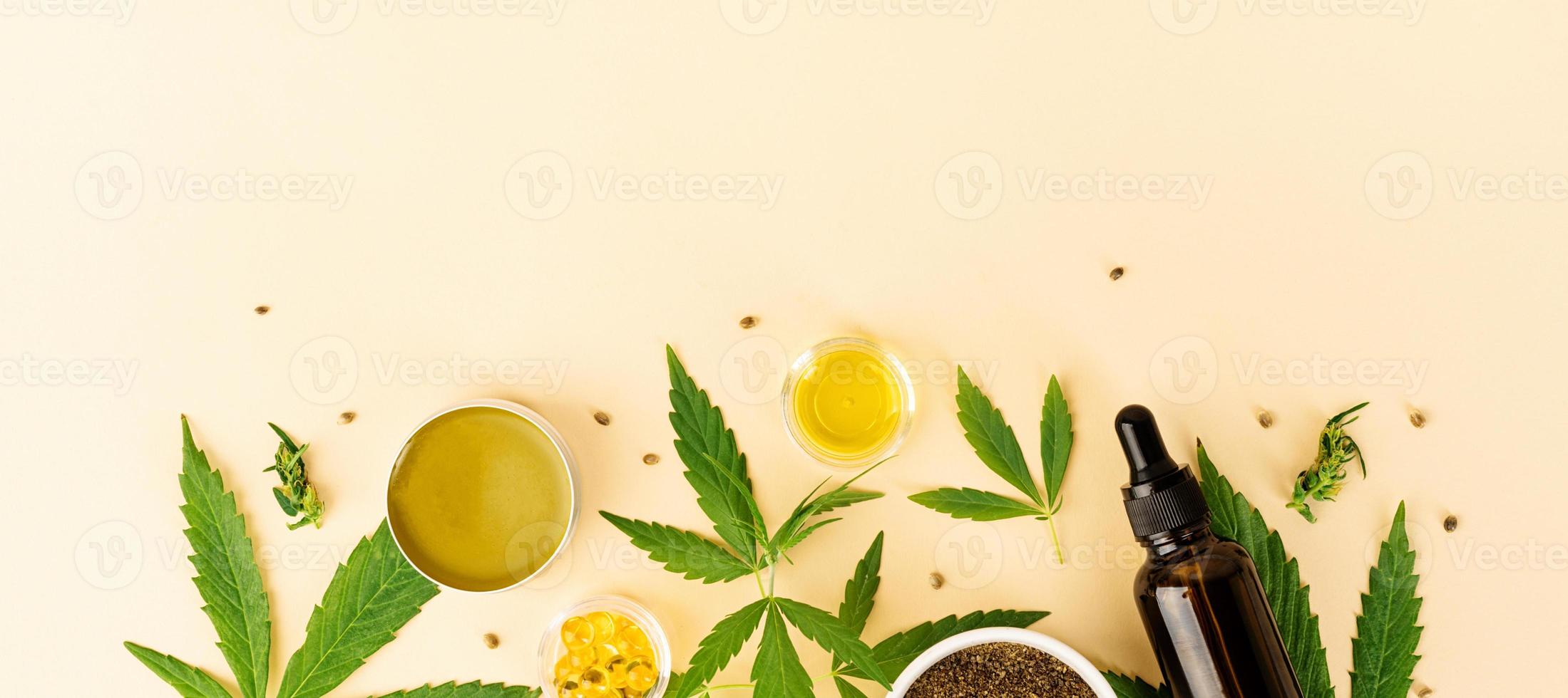 Cbd oil and cannabis leaves cosmetics top view on orange background photo