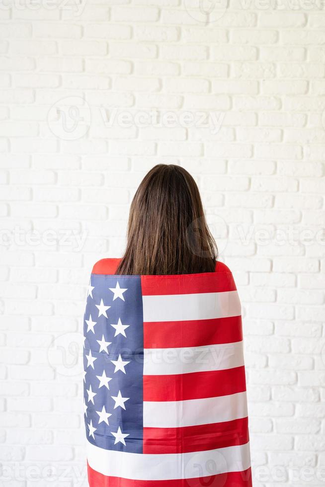 hermosa mujer joven con bandera americana, vista trasera foto