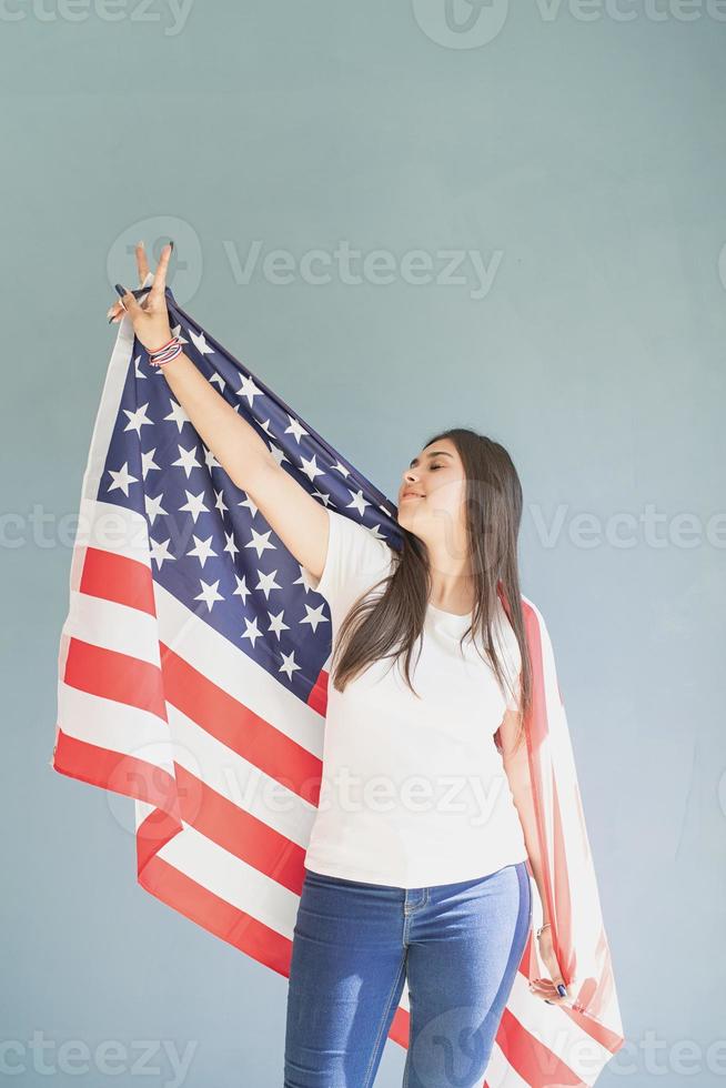 Hermosa mujer joven con bandera americana sobre fondo azul. foto