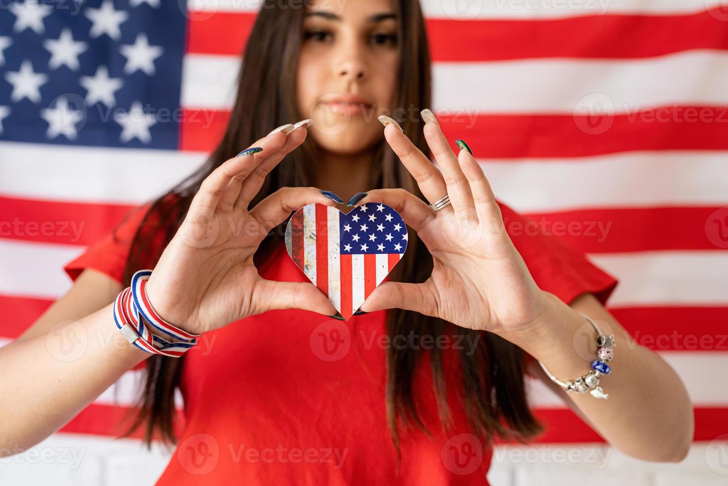 Mujer sosteniendo una pequeña bandera nacional en el fondo de la bandera de Estados Unidos foto